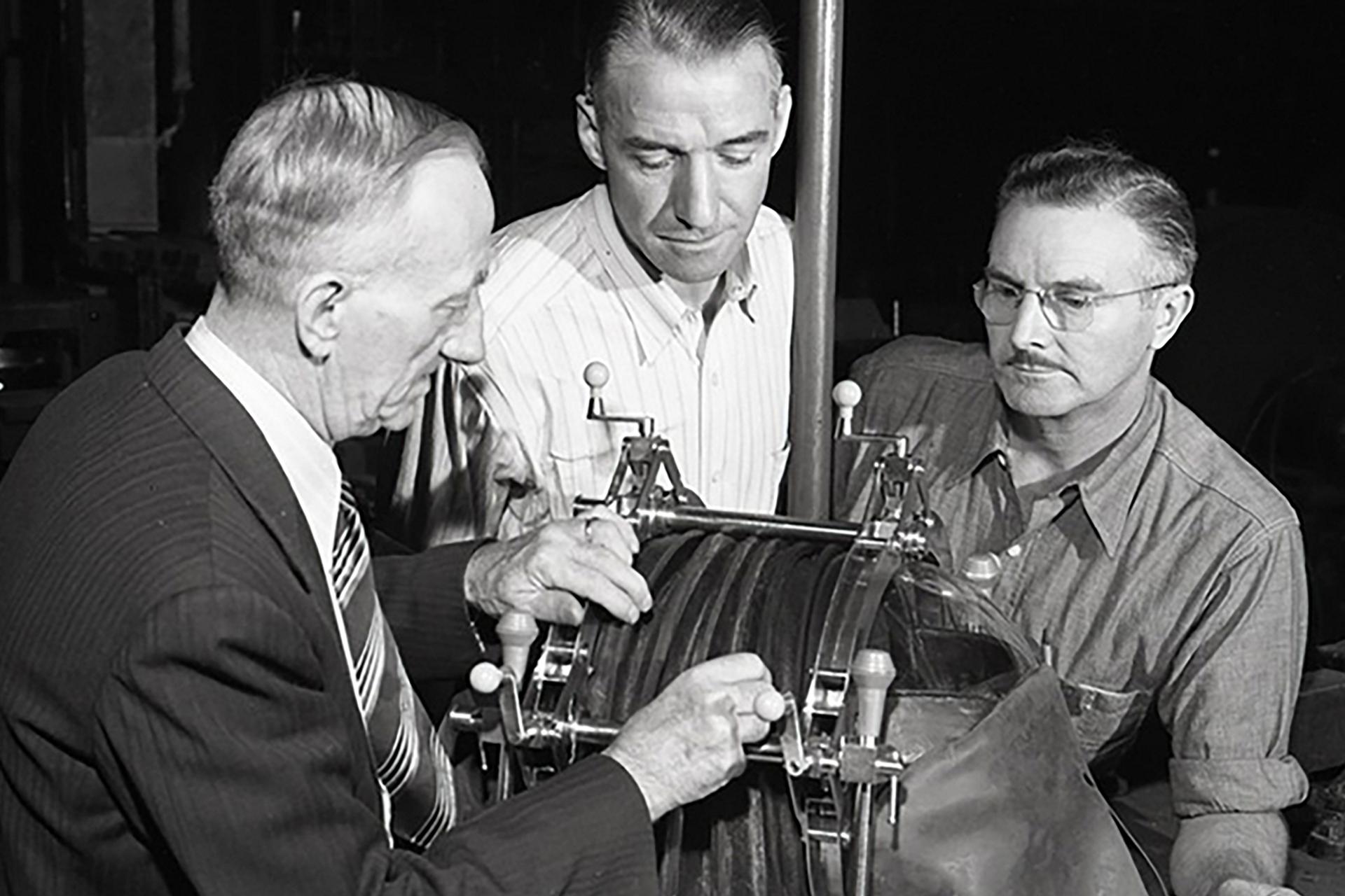 Black and white image of 3 men with an iron lung