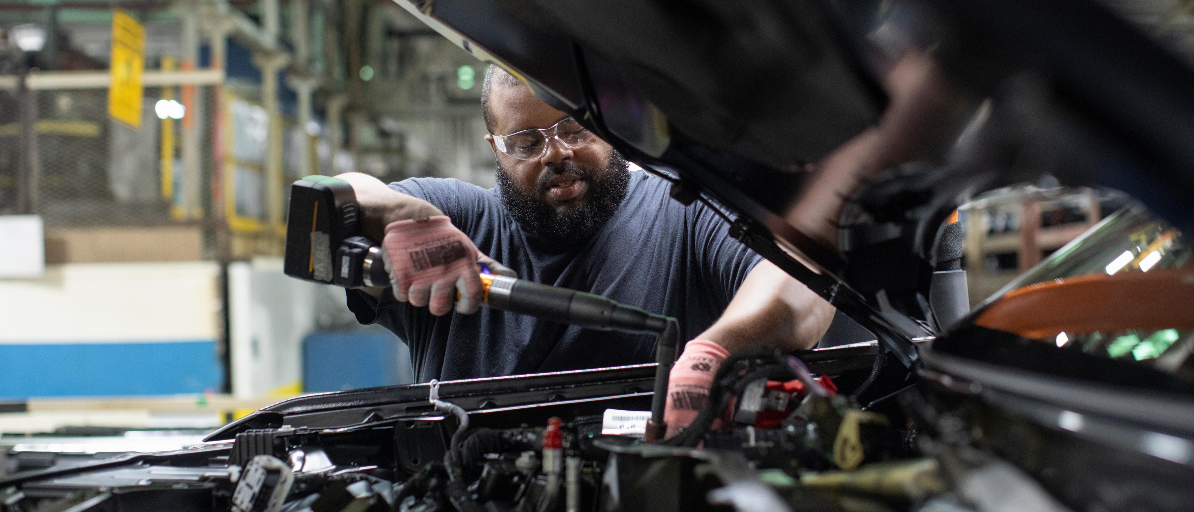 A Ford technician works under the hood of a Ford vehicle