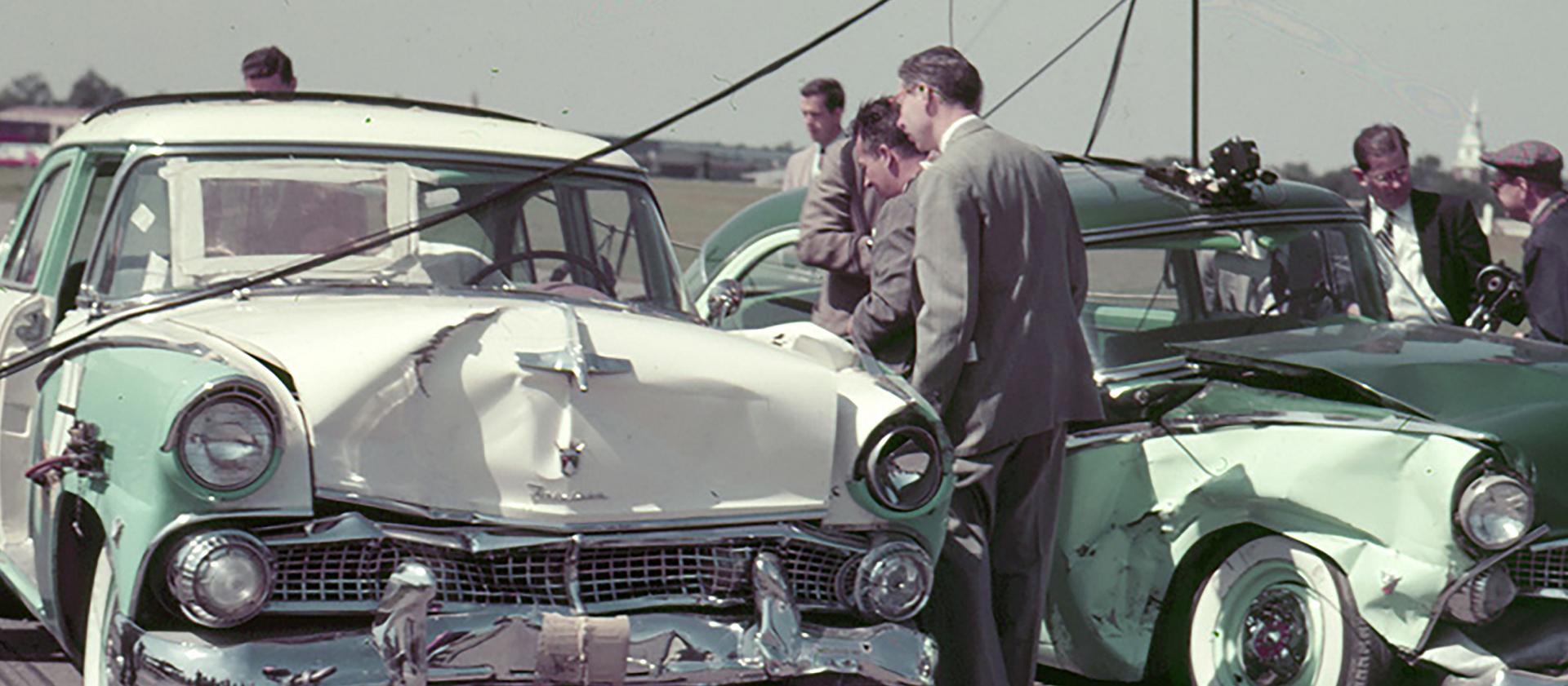 A group of men looking at two vehicles that crashed