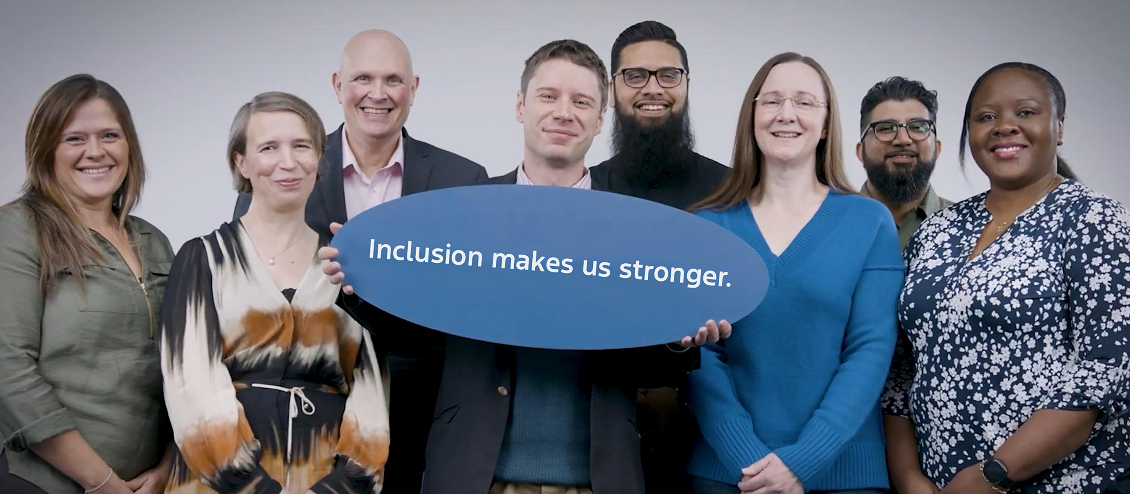 A group of Ford team members stand together, one member holds a sign that reads inclusion makes us stronger