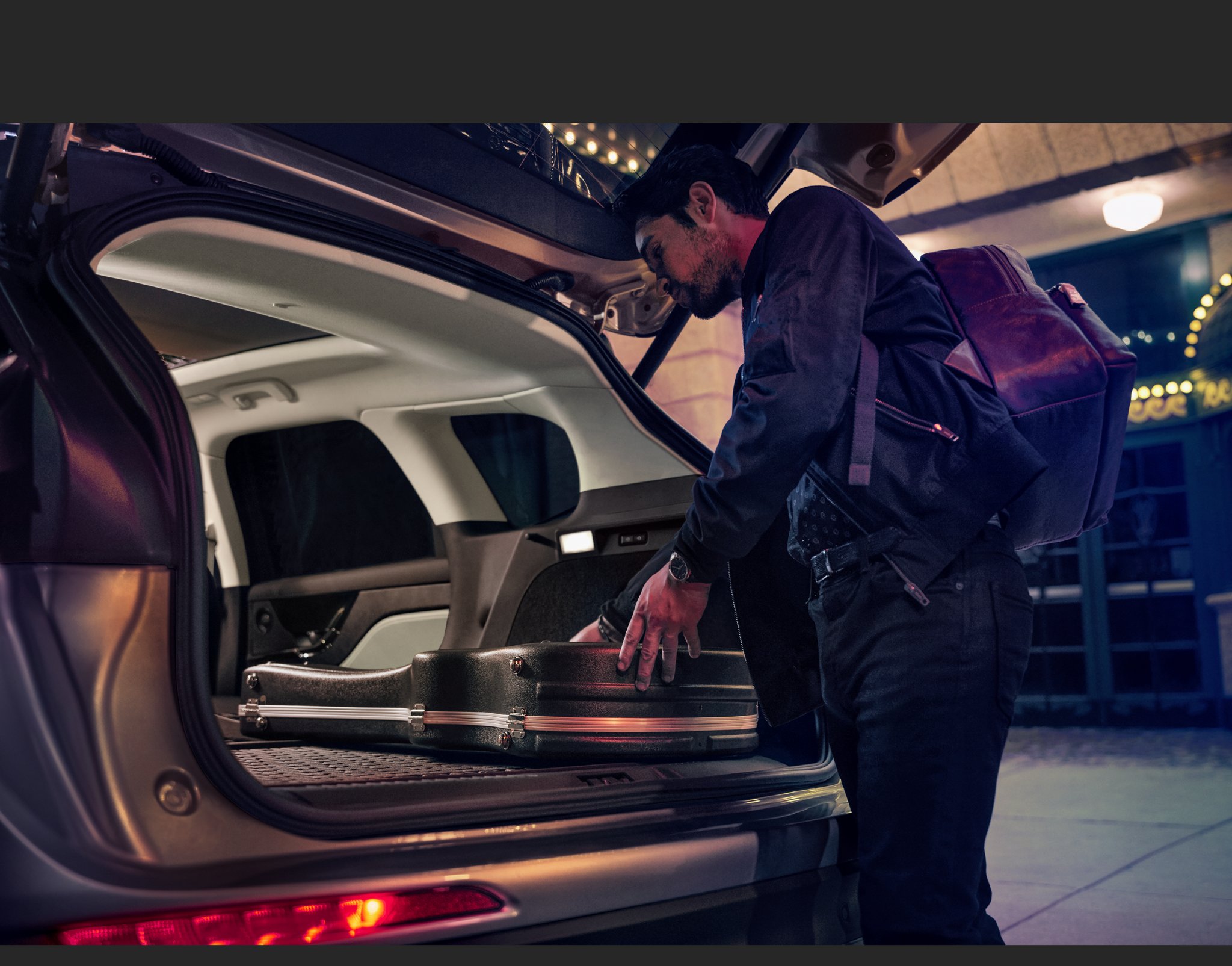 A musician loads musical equipment in the rear cargo area of a 2026 Lincoln Corsair