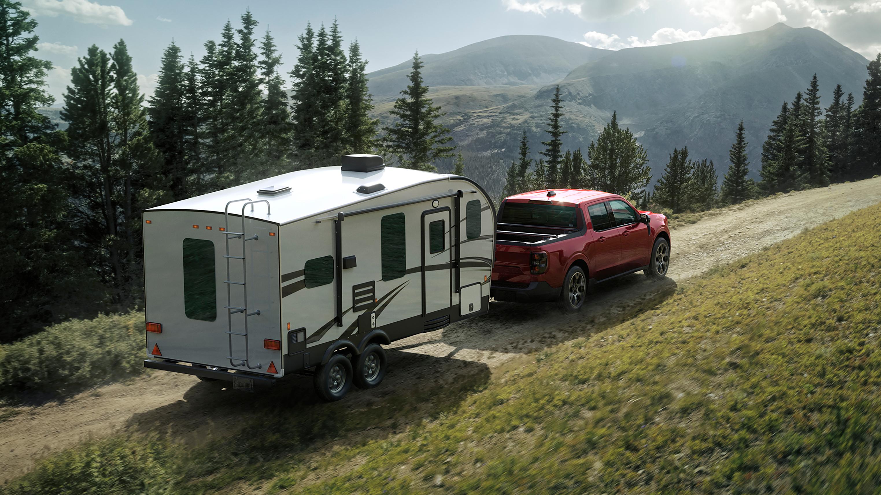 2026 Ford Maverick® Lariat pickup in Ruby Red Metallic Tinted Clearcoat (extra cost) pulling a camper on a mountain pass