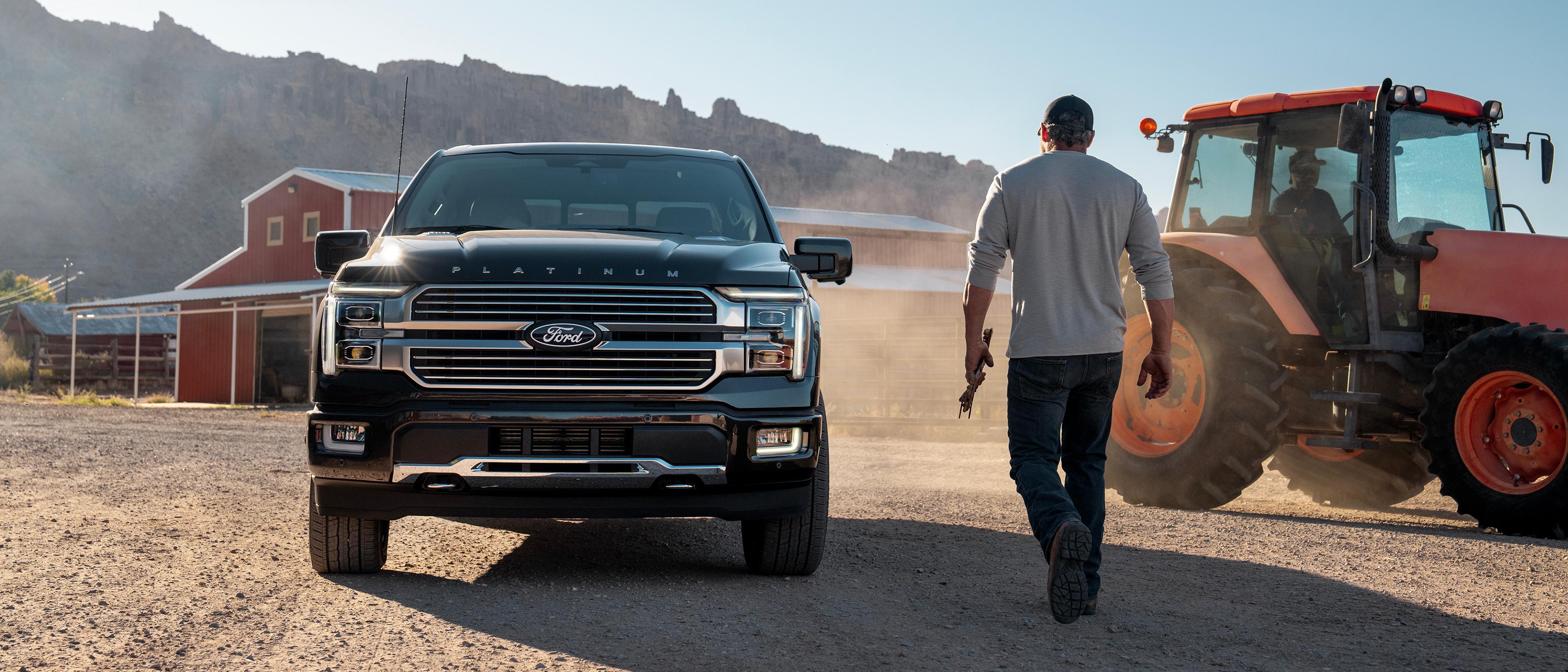 Man walking up to a 2024 Ford F-150® Platinum® hybrid truck on a farm