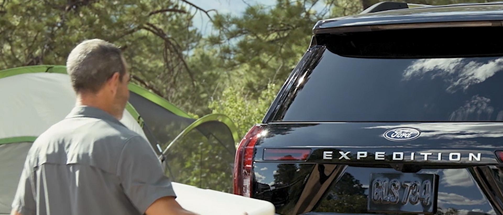 A person using the Ford Split Gate with available Open On Approach to load a cooler in a 2026 Ford Expedition® SUV