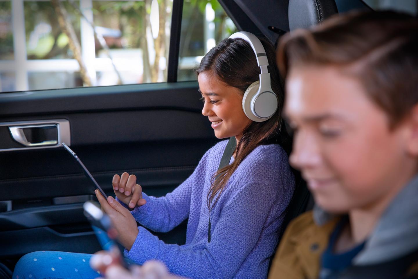 Children using mobile devices in the backseat of a vehicle