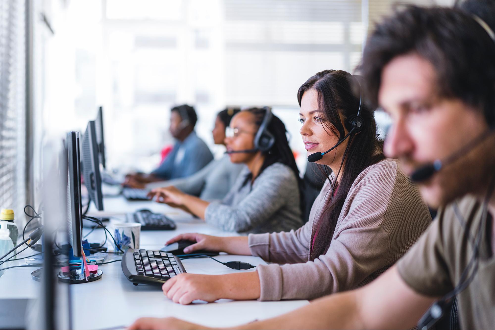 People waring headphones and sitting inside a call center