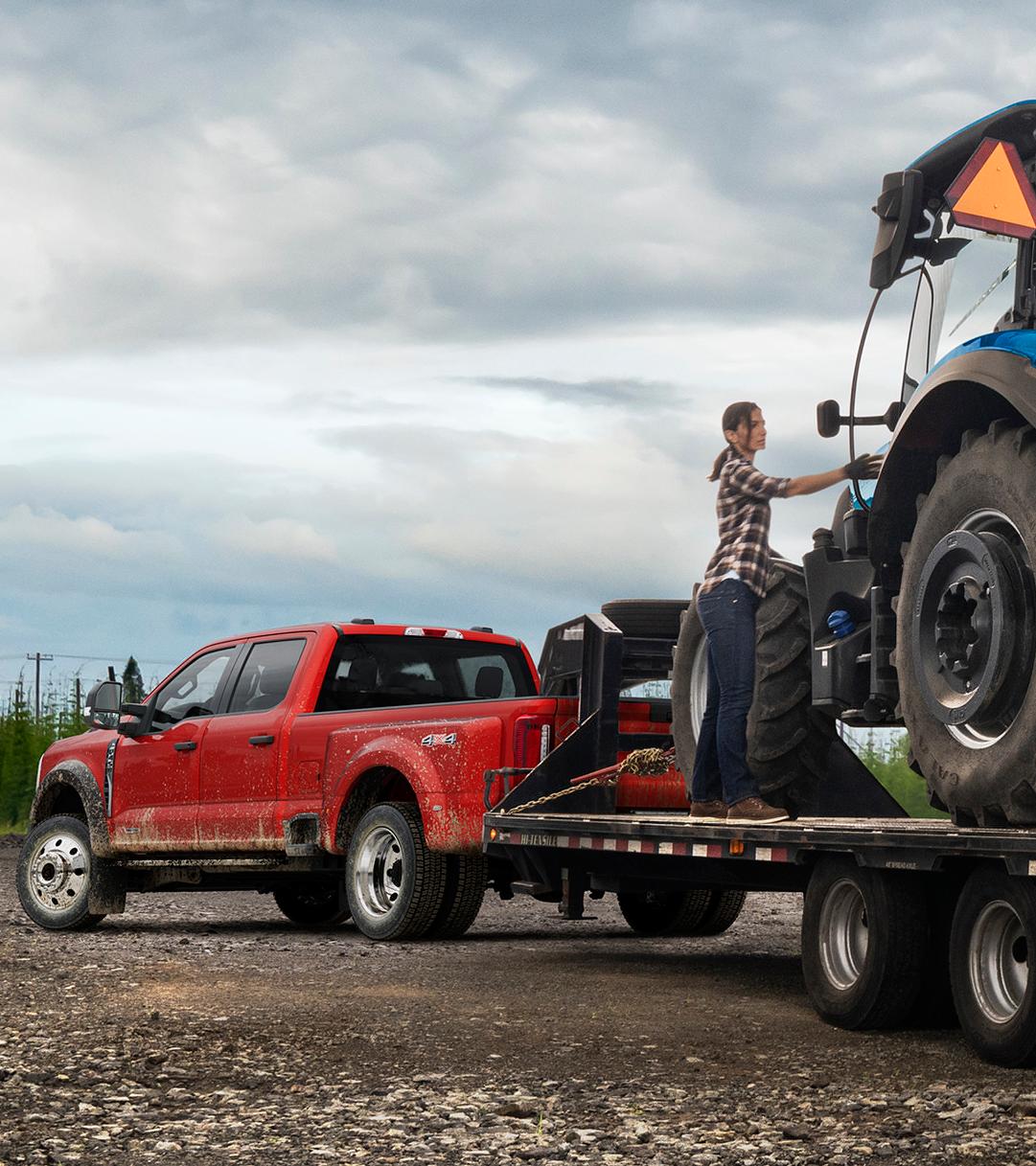 A Ford Super Duty® truck hauling a trailer with a tractor on it