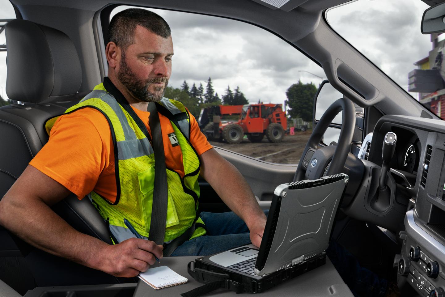 Worker using tablet inside of a 2025 Ford Super Duty® Chassis Cab at worksite