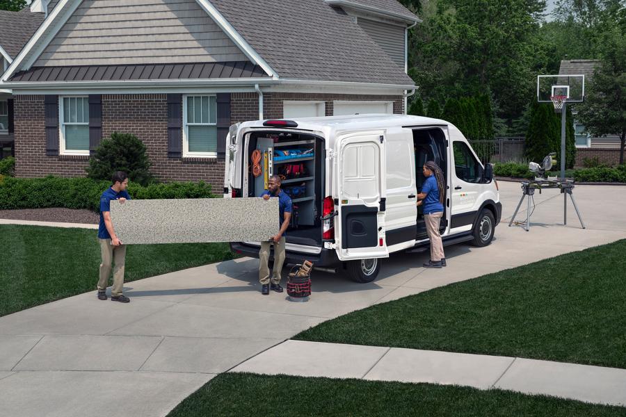A crew of workers unloading a large slab of granite from a 2025 Ford Transit® van