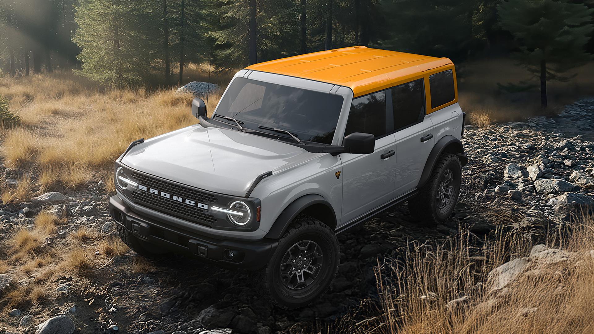 A 2026 Ford Bronco® SUV on a muddy path, with a dark-colored body and a blue roof