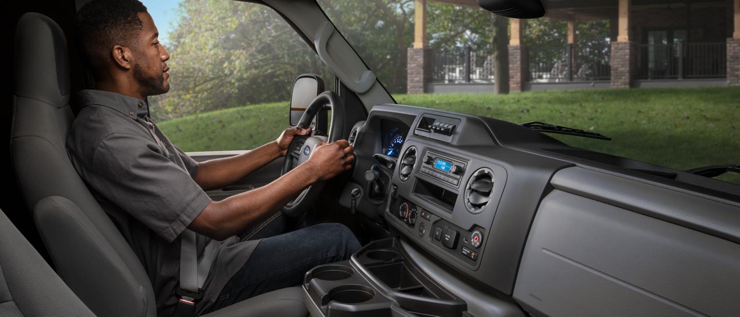 A man in the driver's seat of a 2026 Ford E-Series Cutaway