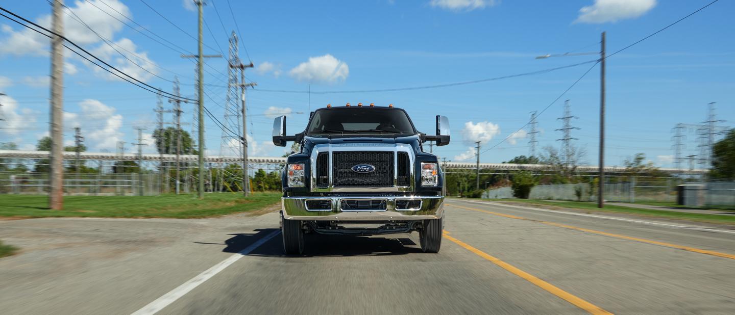 Ford F-750® 2025 à cabine six places en noir agate circulant sur la route près de lignes téléphoniques