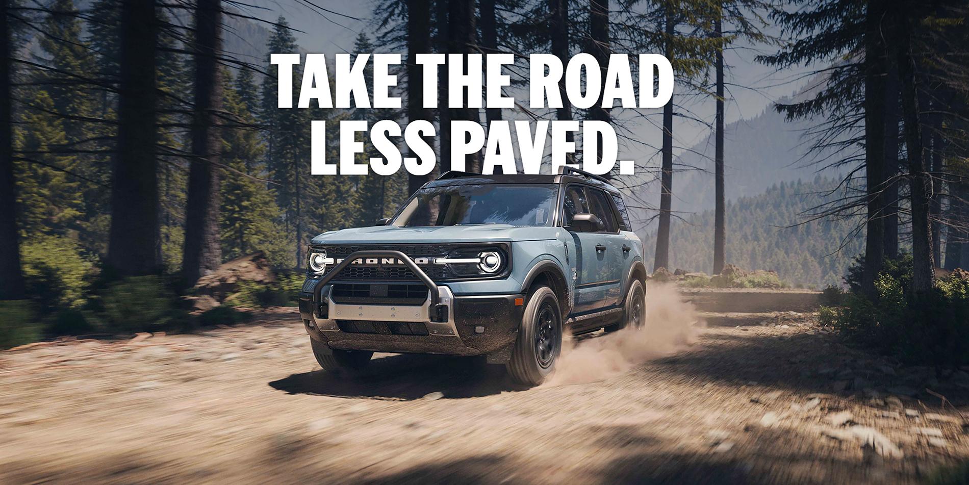 A blue 2025 Ford Bronco Sport® Outer Bank® model being    driven through a forest, going off-road  