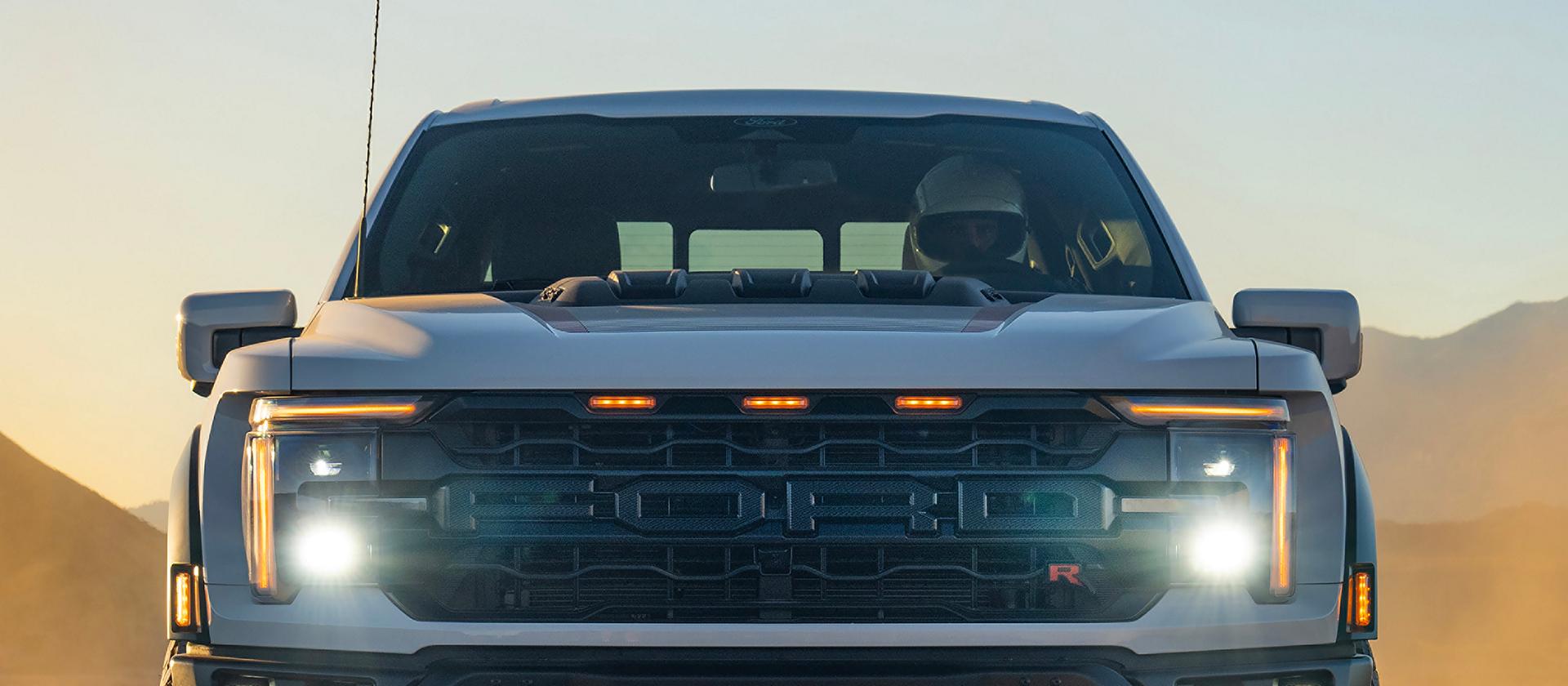 Close-up on the front on a 2026 Ford F-150® Raptor® model with driving lights turned on