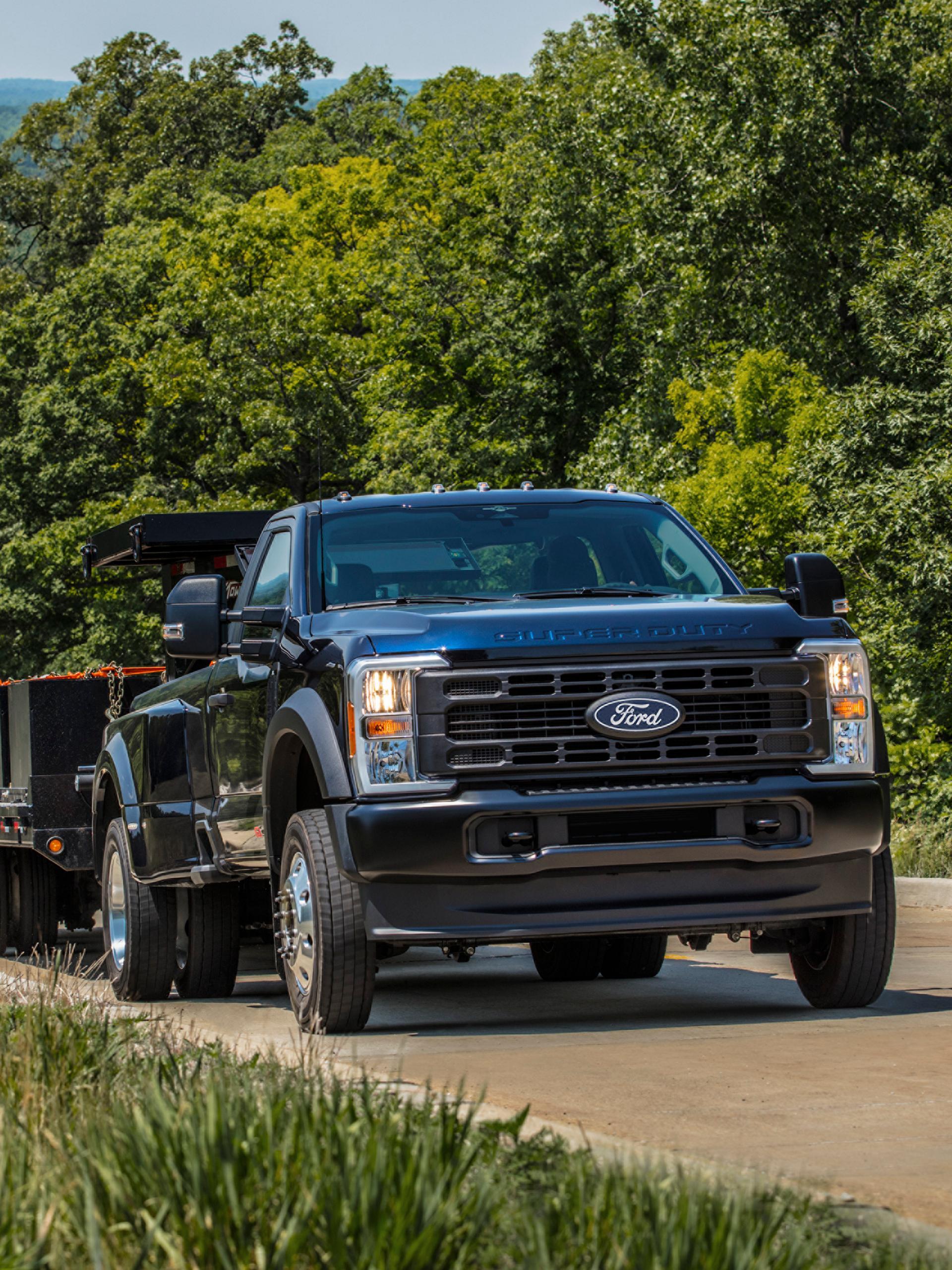 2027 Ford Super Duty® pickup pulling a large flat bed trailer up a paved hill