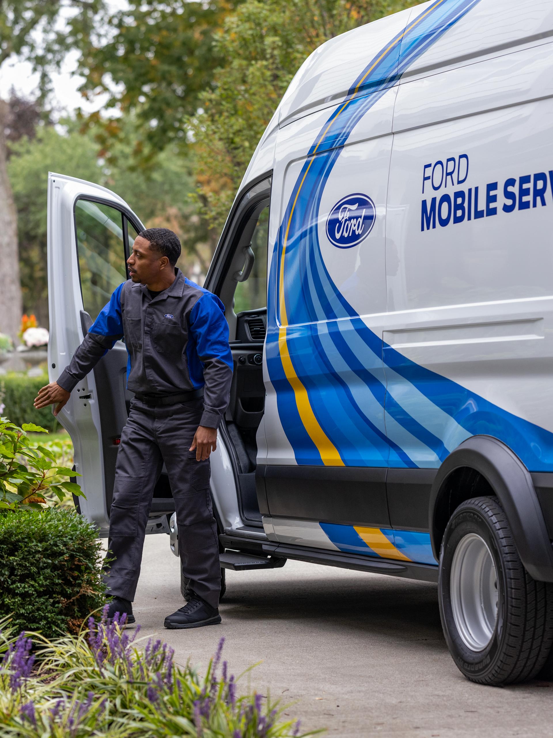A Ford service tech exits their Ford Mobile Service van in a customer’s driveway