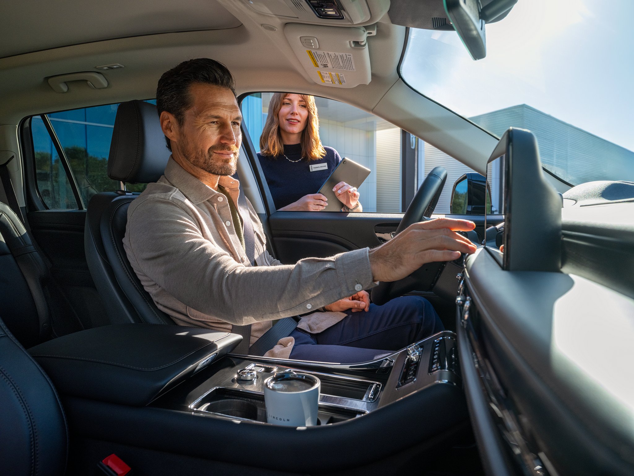 A man sitting inside a Lincoln vehicle and touching the center touch screen
