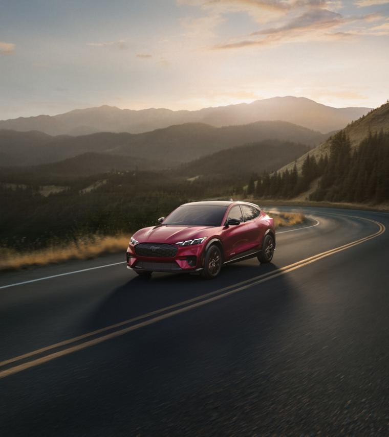 2025 Ford Mustang Mach-E driving on road through rolling hills