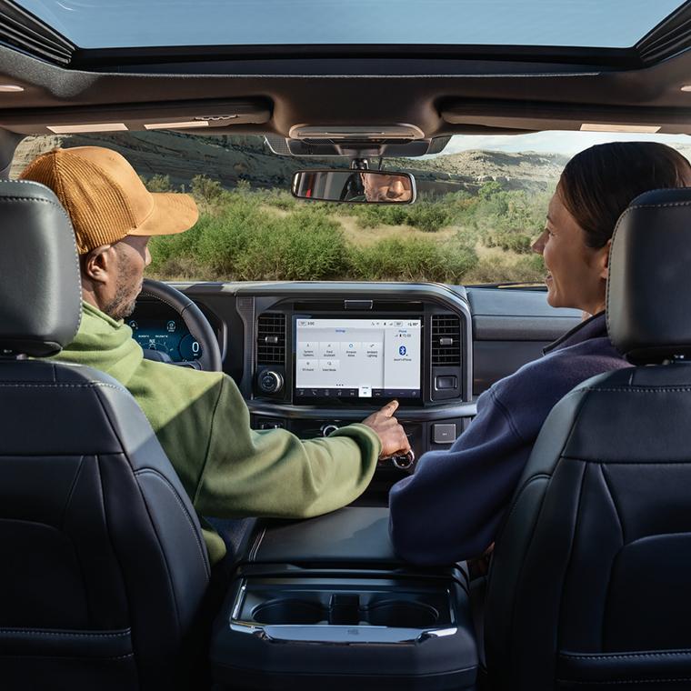 An interior shot of the front two seats of a 2026 Ford F-150® truck with a man and a woman talking