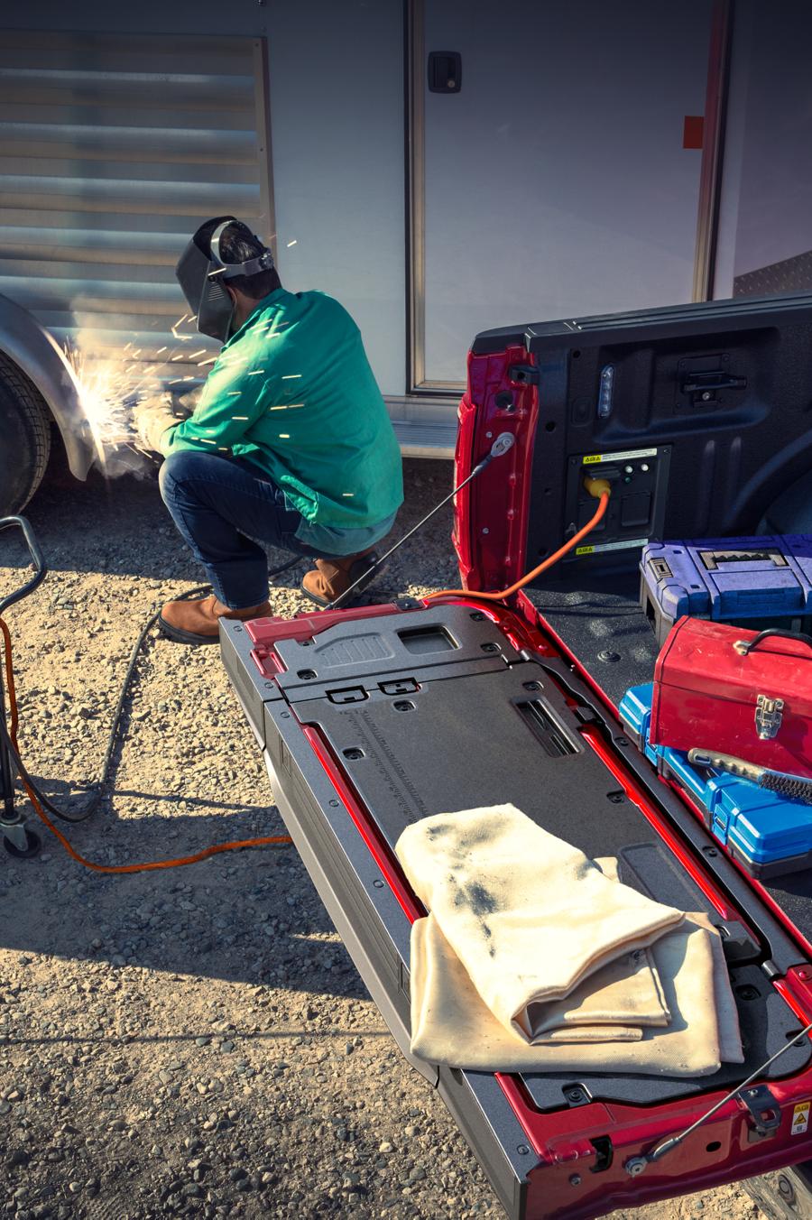 A person using the power outlets in the cab of their Ford F-150® truck to help fix a repair on their camper trailer