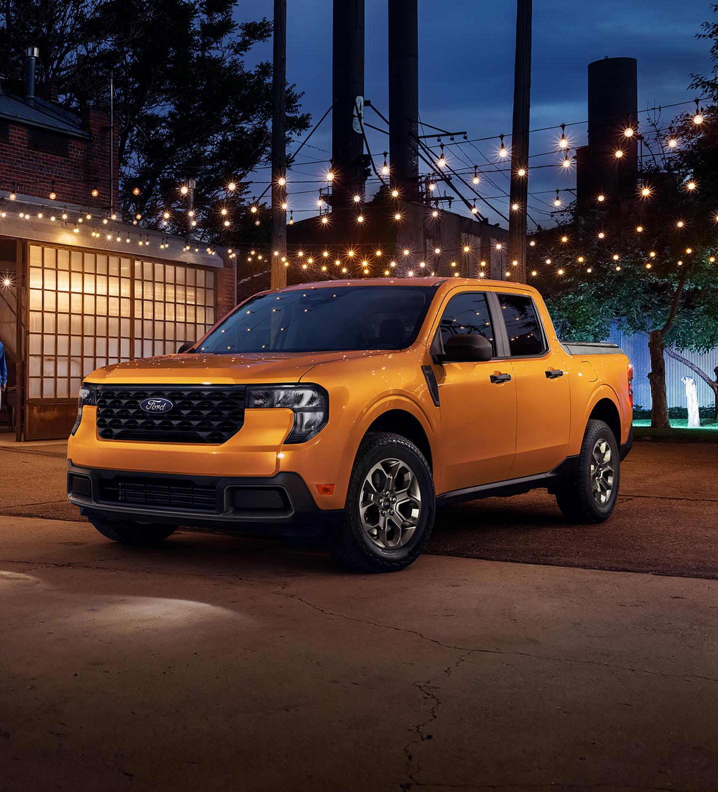 2026 Ford Maverick® XLT model in Orange Fury parked under lights next to a building at night