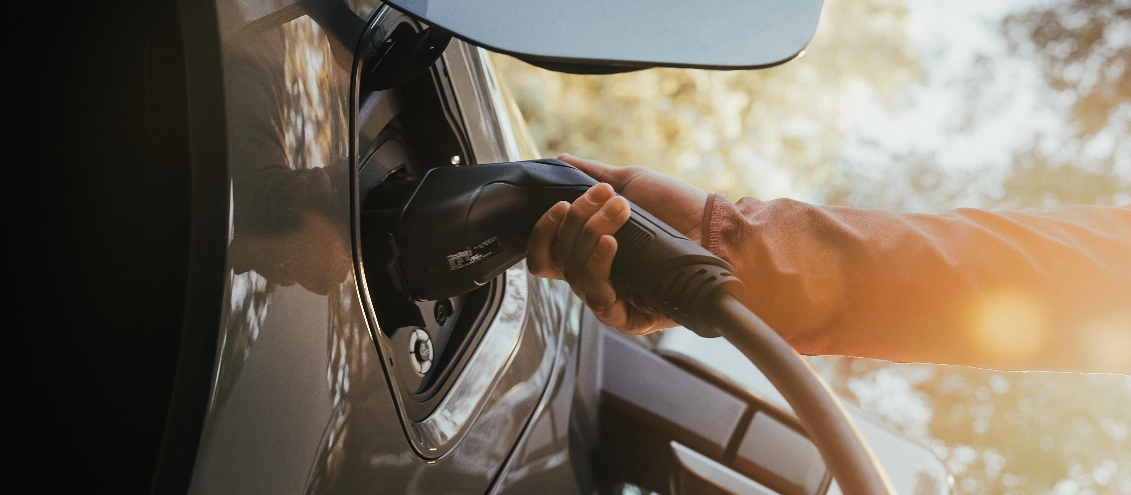 The charge port on a 2025 Ford F-150® Lightning pickup, with a hand holding the charger plug