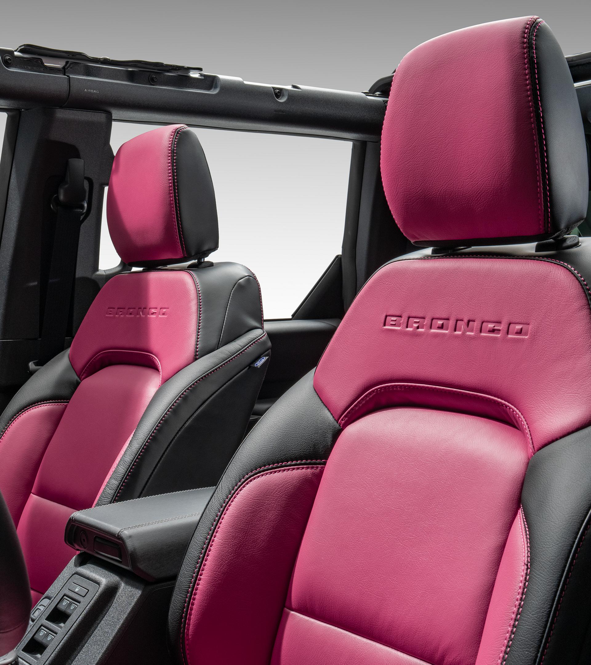 Interior view of custom Katzkin premium leather front seats in black and magenta with embossed BRONCO lettering on the seatback.
