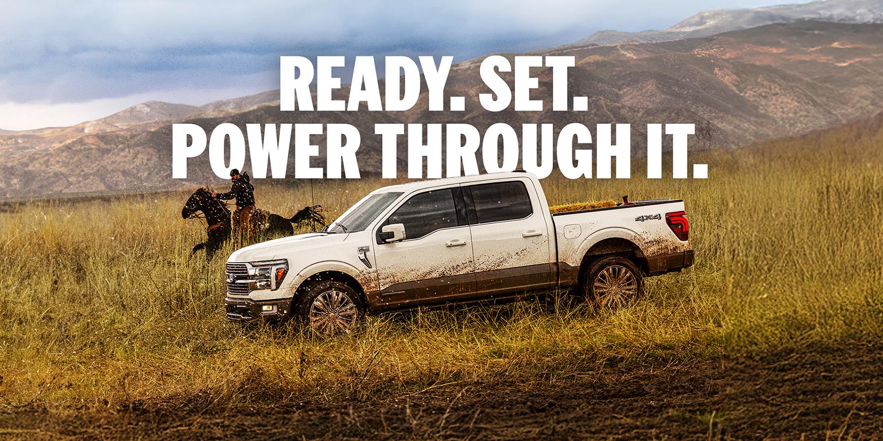 A white 2025 Ford F-150® King Ranch® model being driven through a field next to a man on a horse with a mountain range in the background