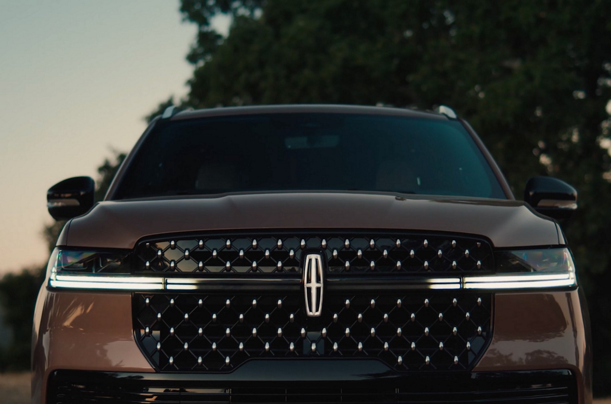 La calandre d’un VUS Lincoln Navigator® 2025 stationné affiche la séquence d’éclairage du Lincoln Embrace