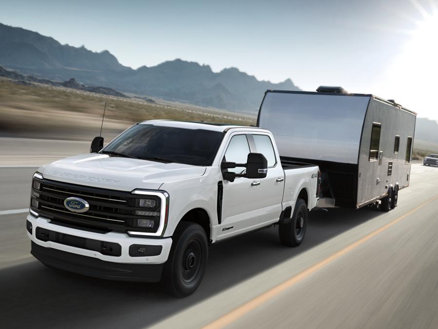 2025 Ford Super Duty® F-350® Platinum® in Star White towing a camper down a road