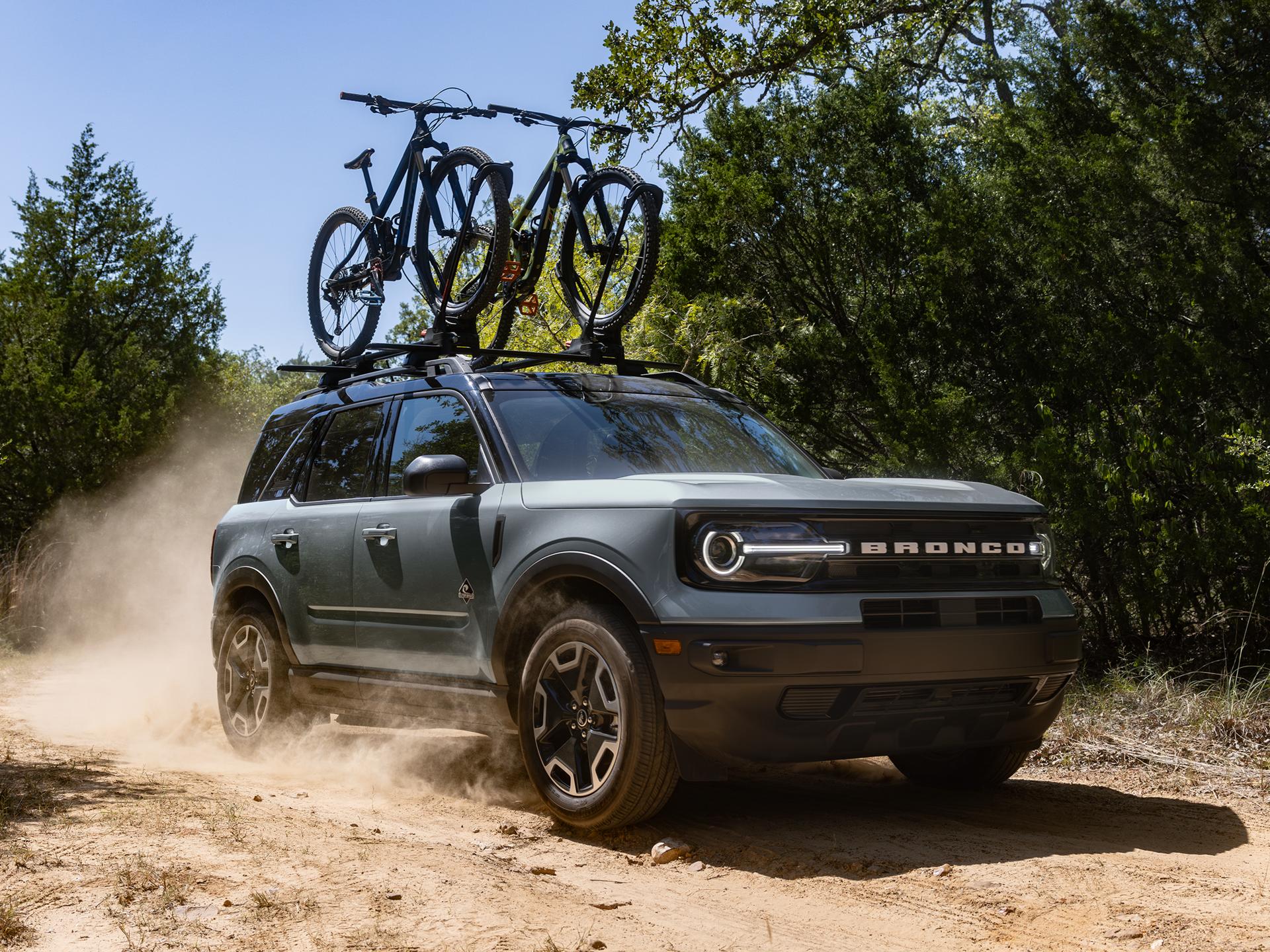 Ford Bronco® Sport being driven on a dirt road with two bikes in the roof rack