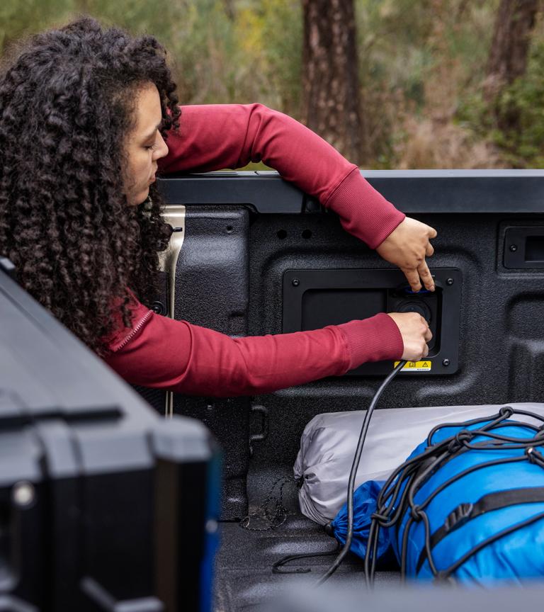 A person plugging a cord into the in-bed outlet on their 2026 Ford Ranger® Lariat® truck