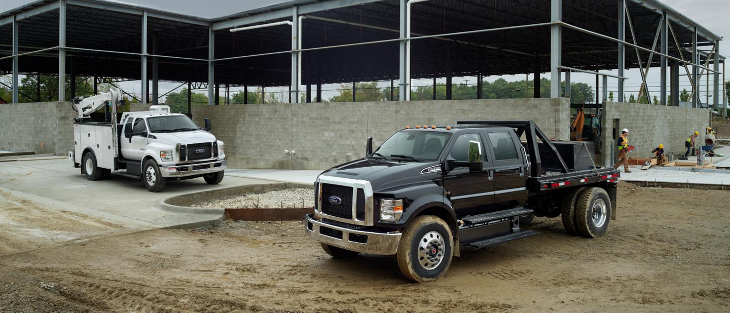 Ford F-750 2025 à cabine double avec aménagement en blanc Oxford et Ford F-750 2025 à cabine six places avec aménagement en noir agate sur un chantier