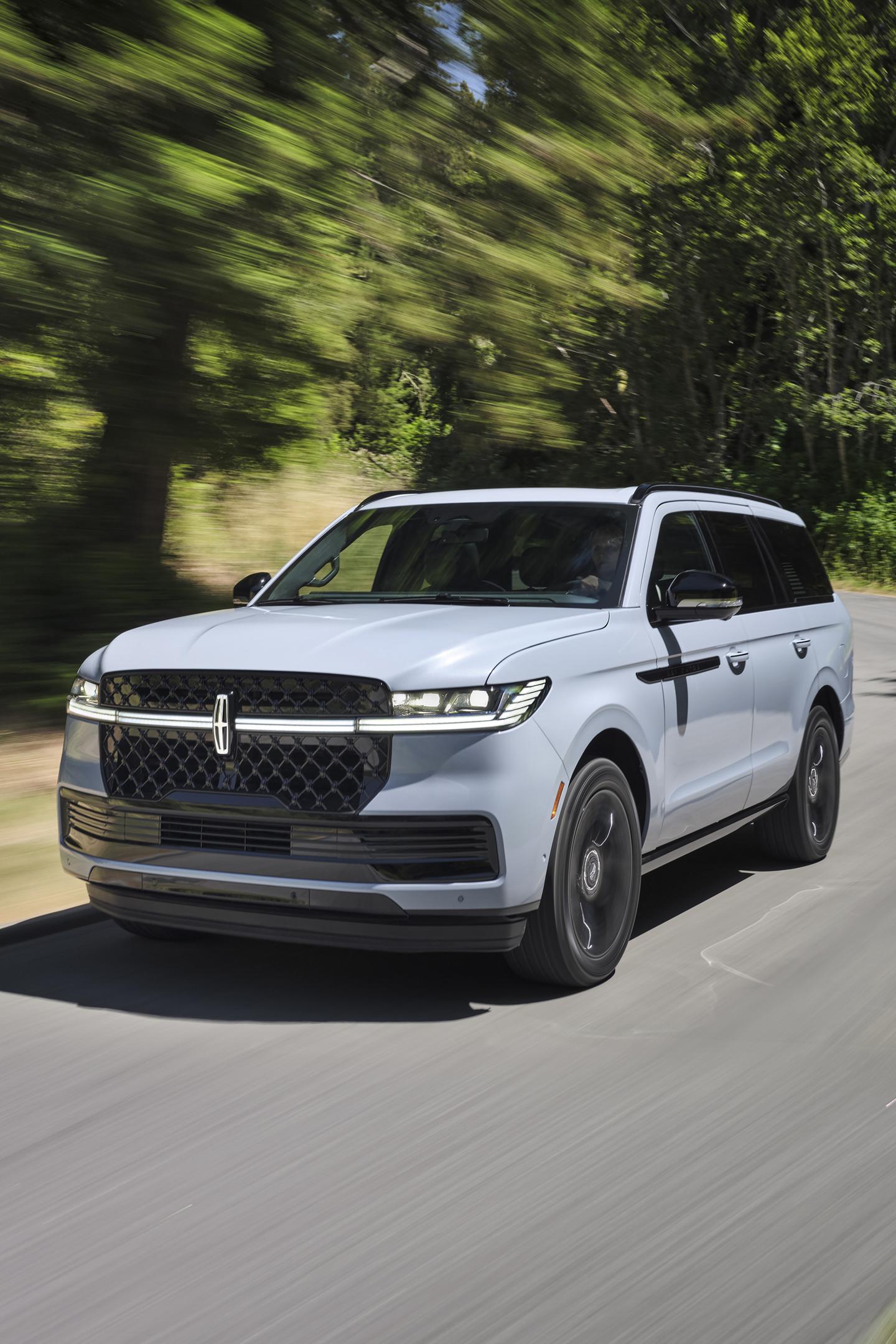 A 2025 Lincoln Navigator® SUV is being driven on a country road