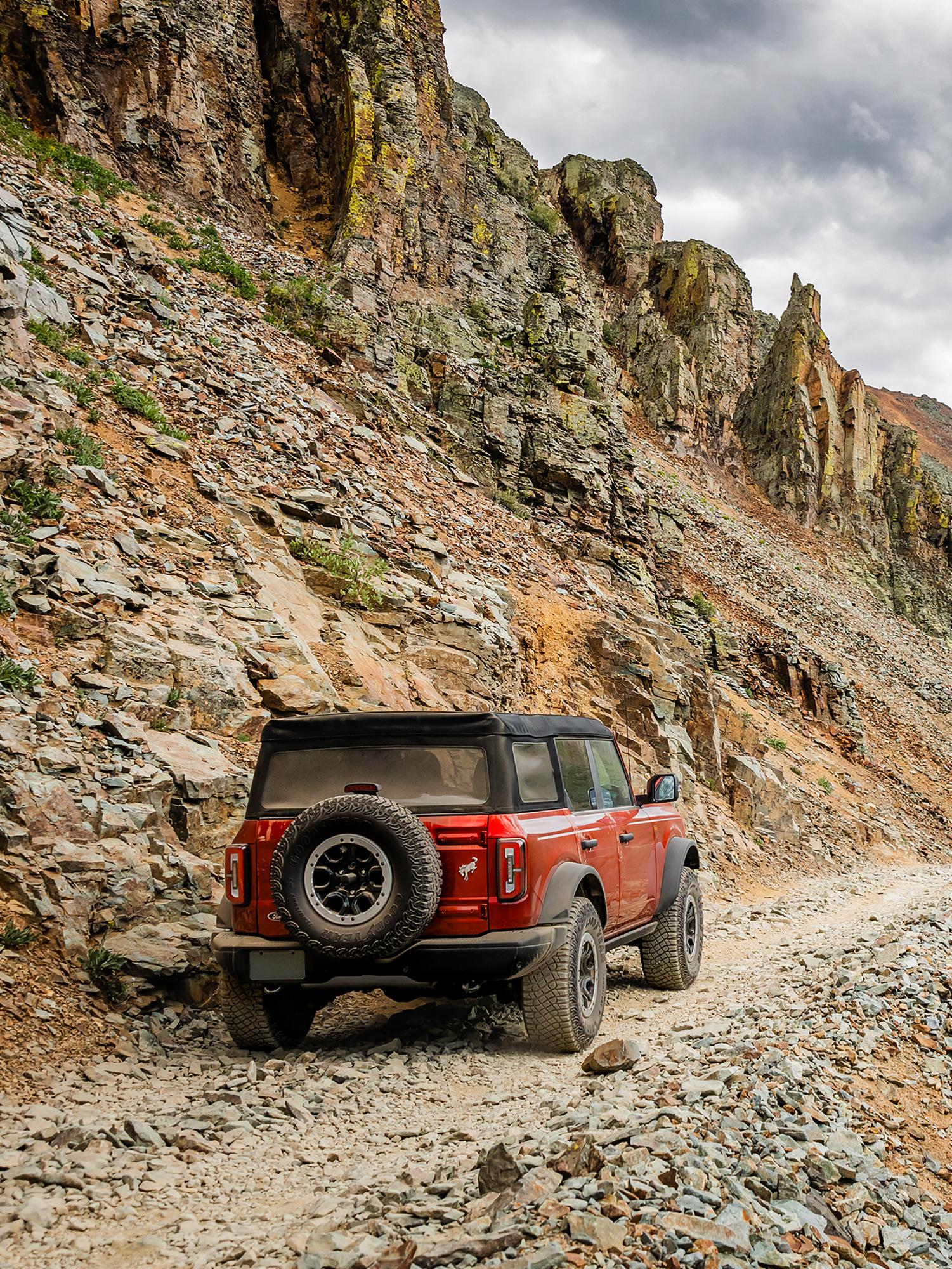 A Ford Bronco® SUV ascends a rocky, two track through the mountains