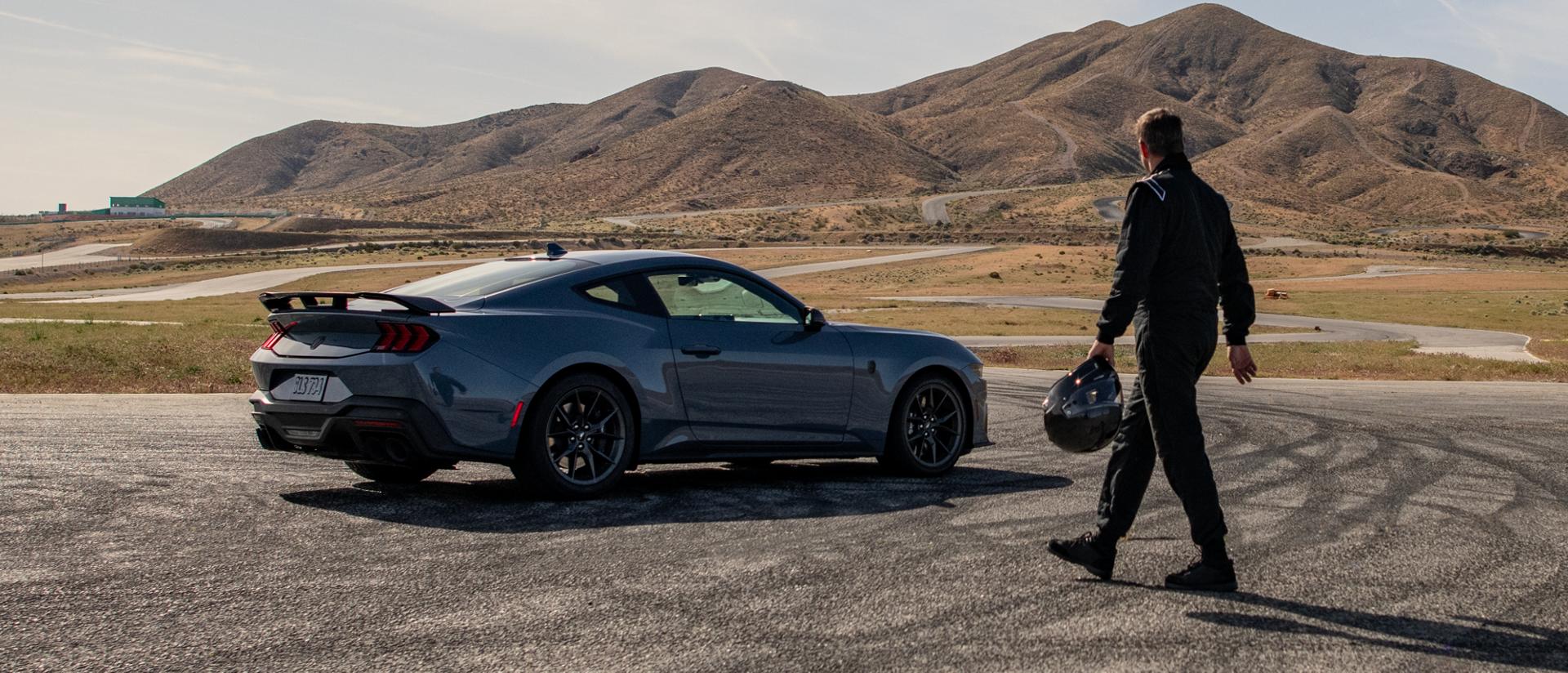 Person holding helmet walking up to a Ford Mustang® car