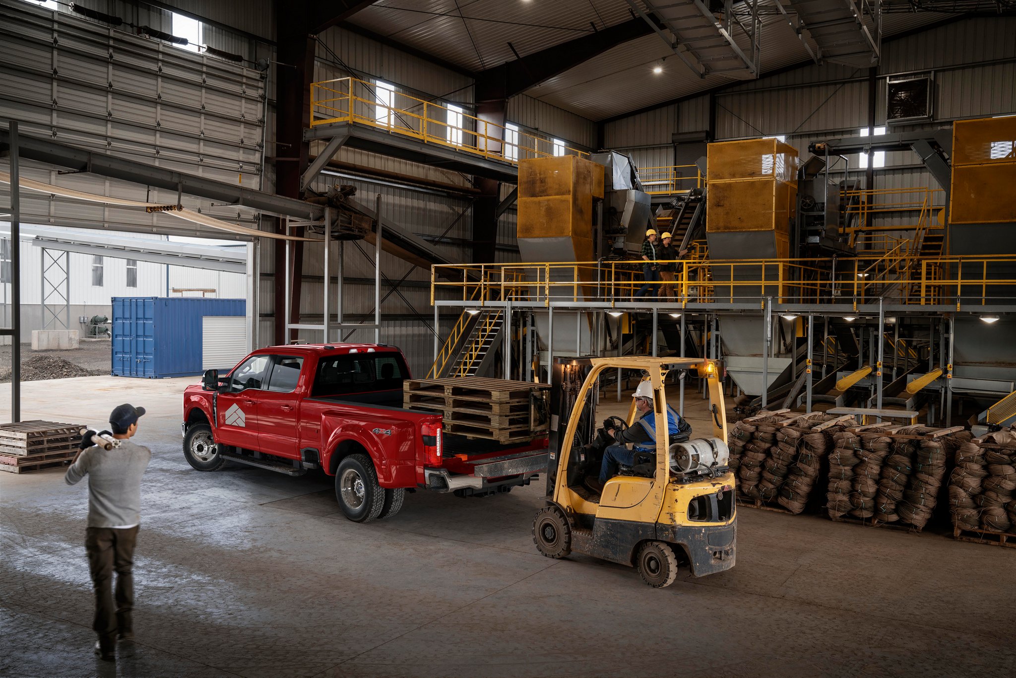 Un homme regardant un chariot élévateur à fourche charger du foin dans la caisse d’une camionnette Ford Super Duty® LARIAT® 2025