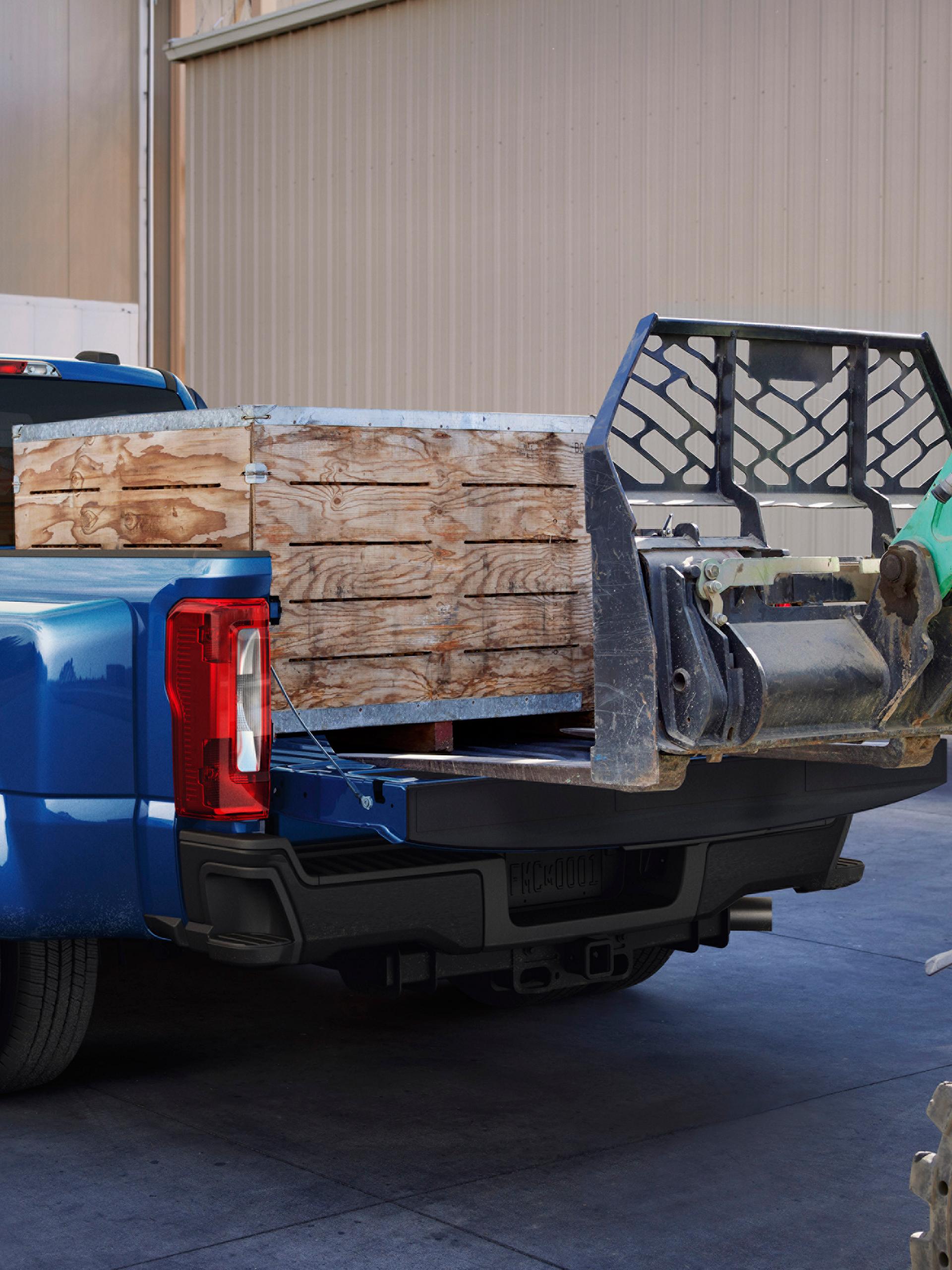 A 2027 Ford Super Duty® F-350® Lariat® model with a heavy crate being loaded into the truck bed