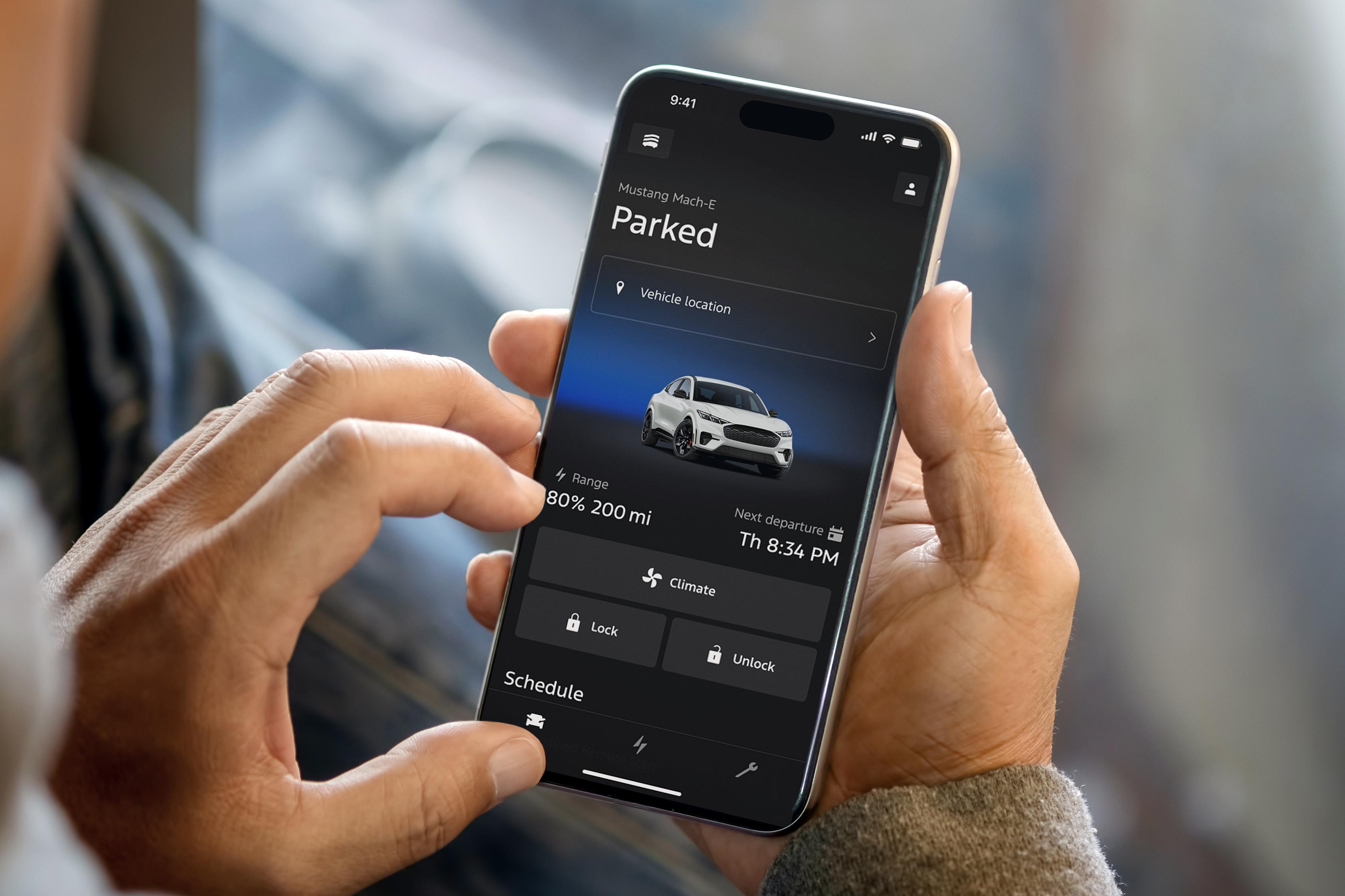 Person holding a smartphone displaying the Ford App interface