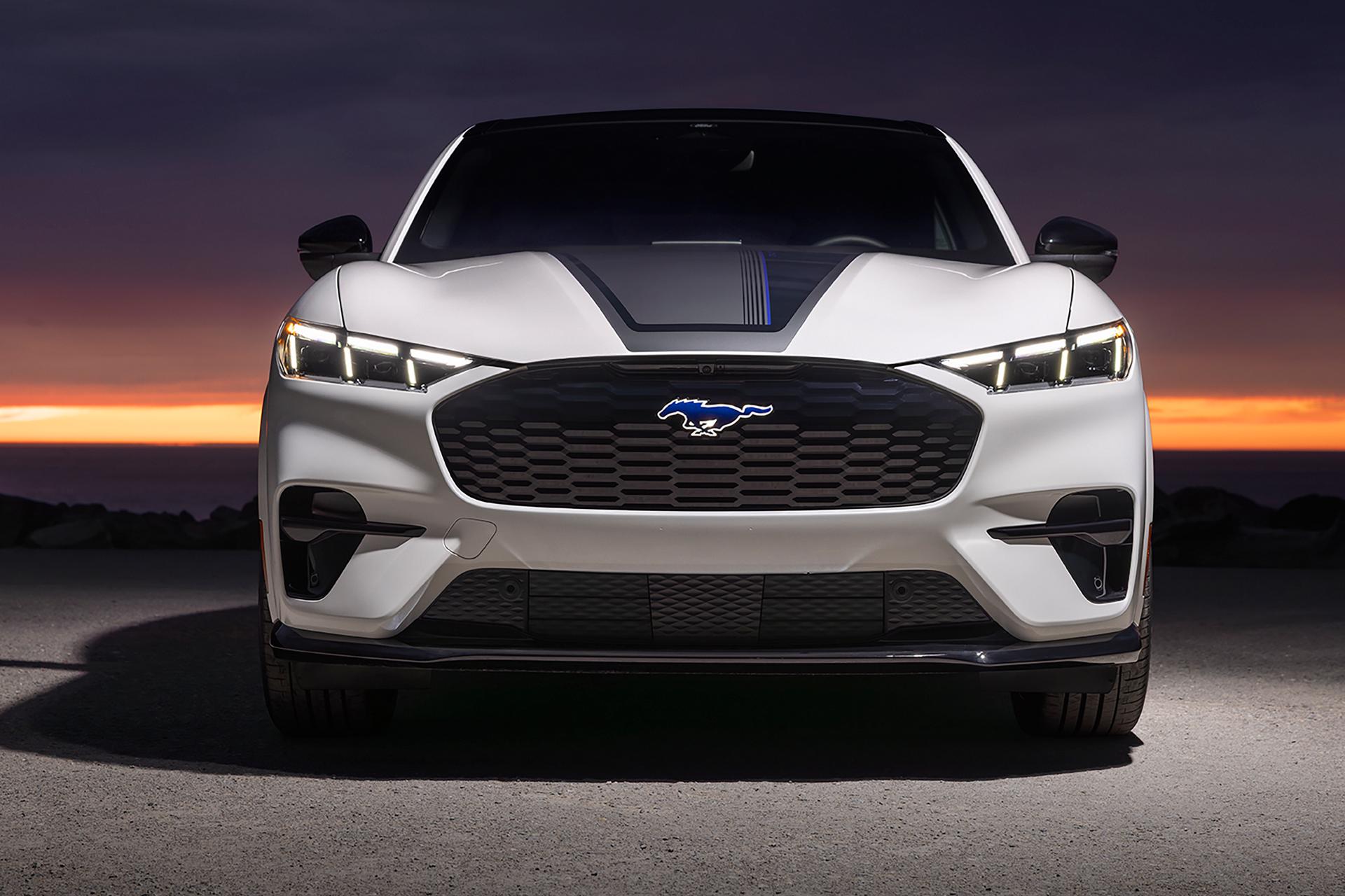Front end of a Mustang Mach-E® GT model with hood stripe against a sunset background