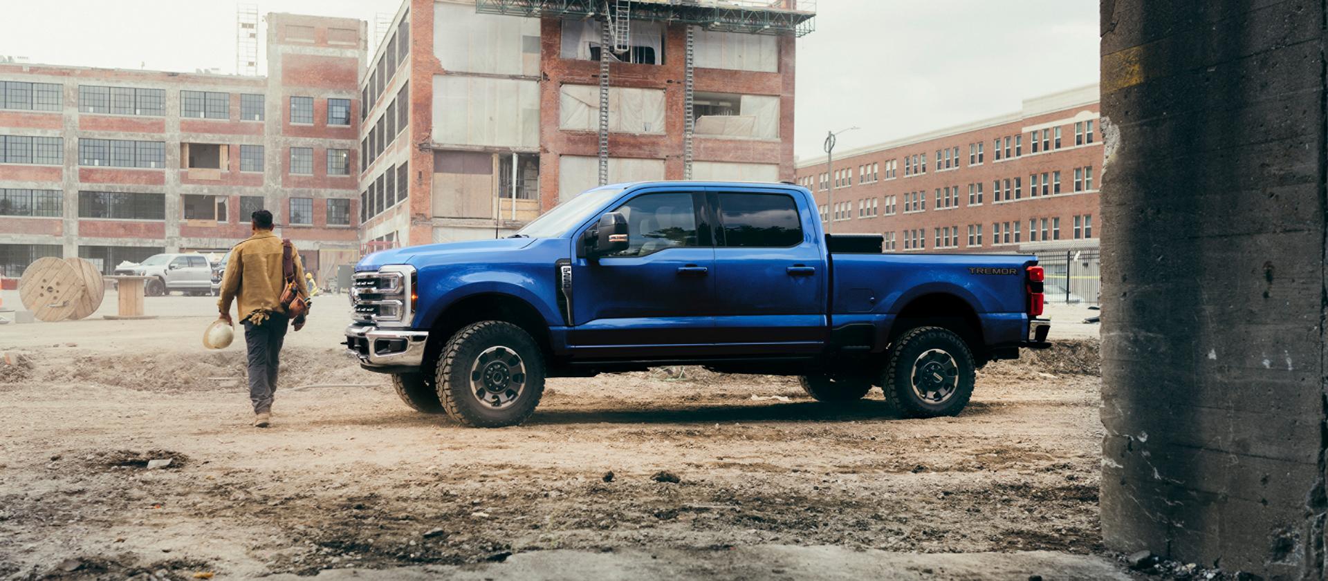 A person walking away from their 2027 Ford Super Duty® F-250® Lariat® pickup in Argon Blue on a construction site