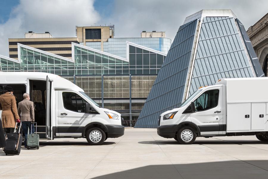 People near a 2025 Ford Transit® model with shuttle bus body and a 2025 Ford Transit® model with aftermarket utility body