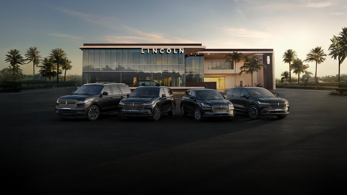 A group shot showcasing Lincoln SUVs parked in front of a modern Lincoln building, with palm trees in the background