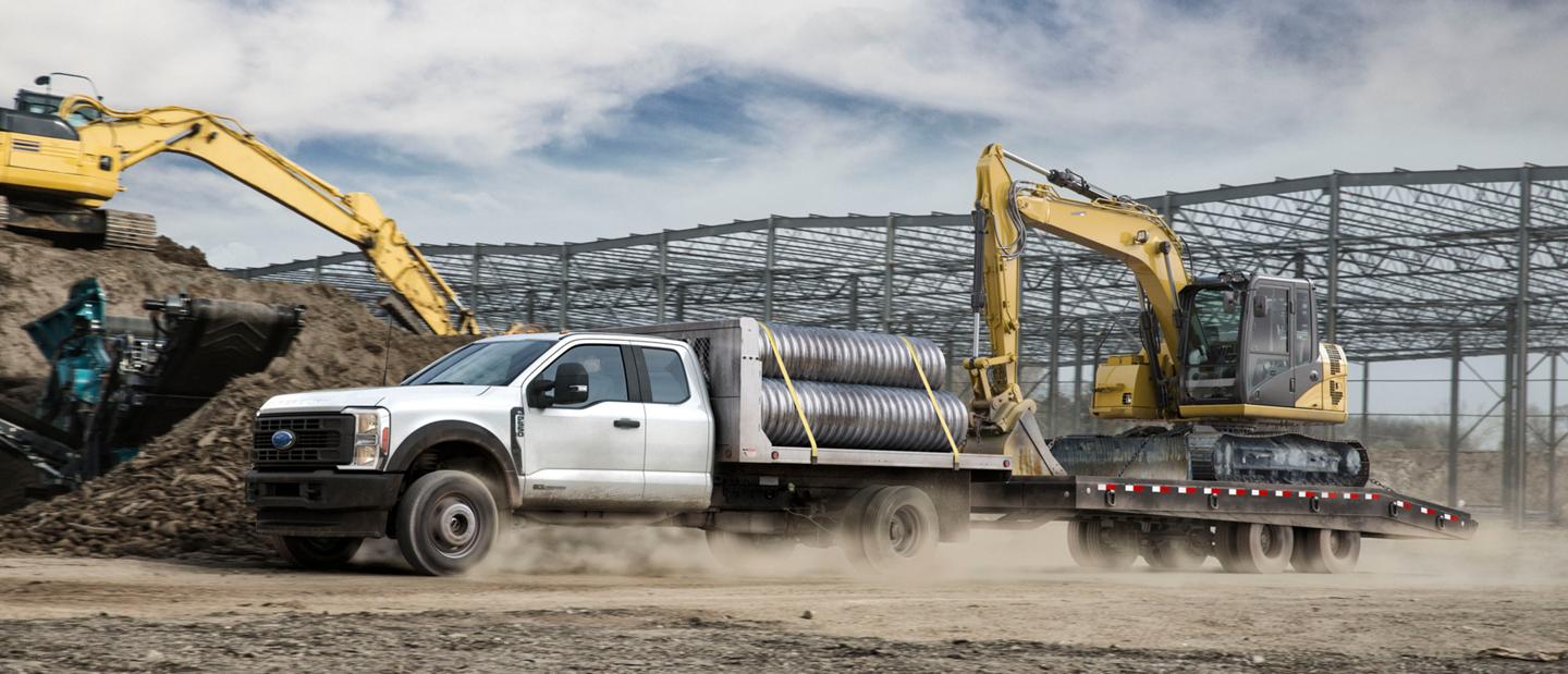 Un Ford F-350® Super Duty® 2025 transportant des tuyaux et faisant une excavatrice