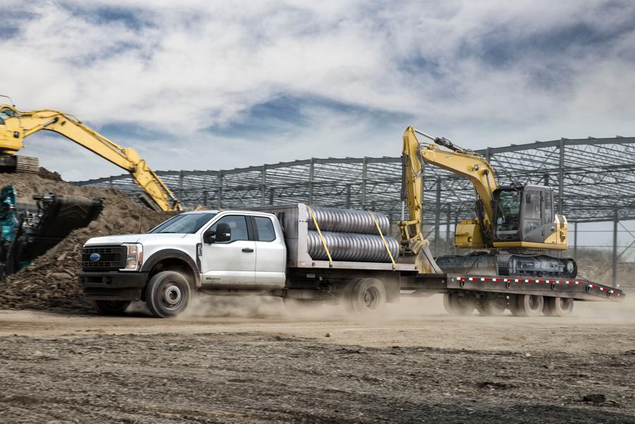 Ford Super Duty® F-350 2025 chargé de tuyaux et tirant une remorque avec une rétrocaveuse