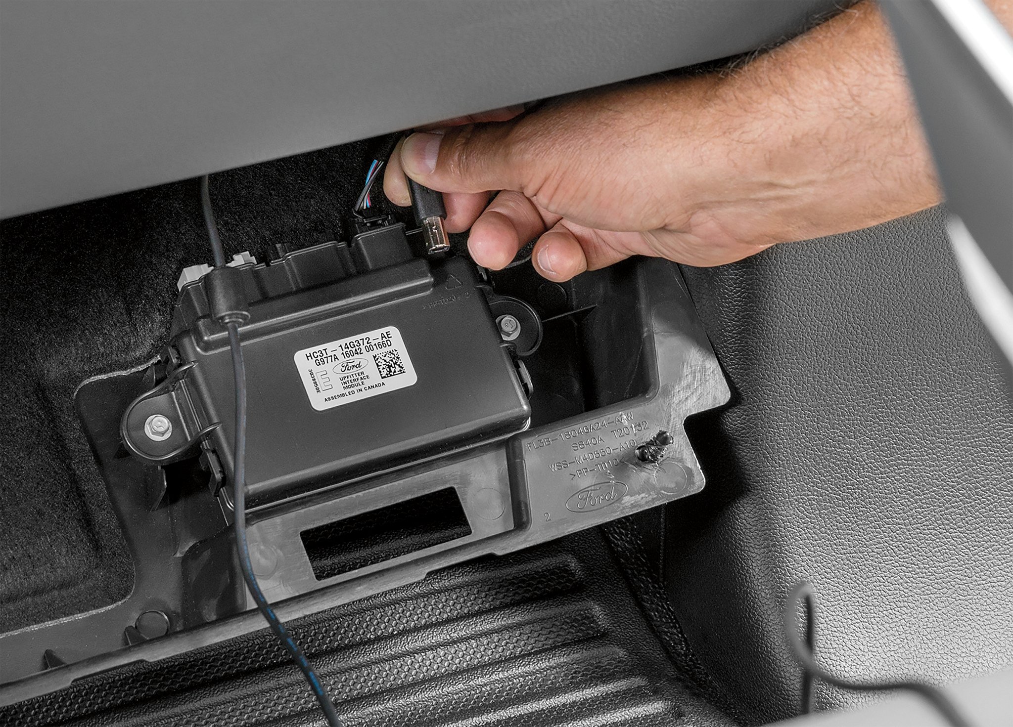 Close-up of a person plugging in upfitter switches into a module