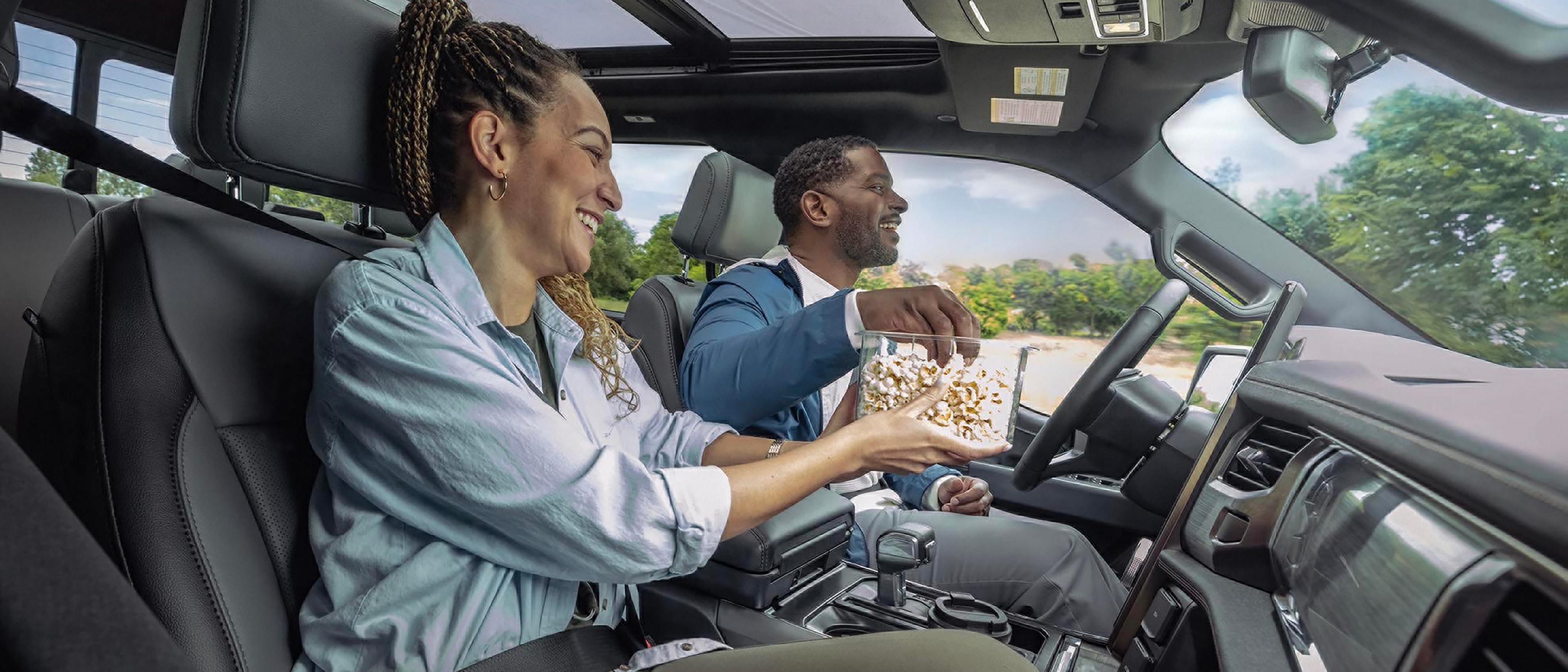 A driver and passenger eating popcorn in a 2025 Ford F-150® Lightning® engaged with the BlueCruise feature