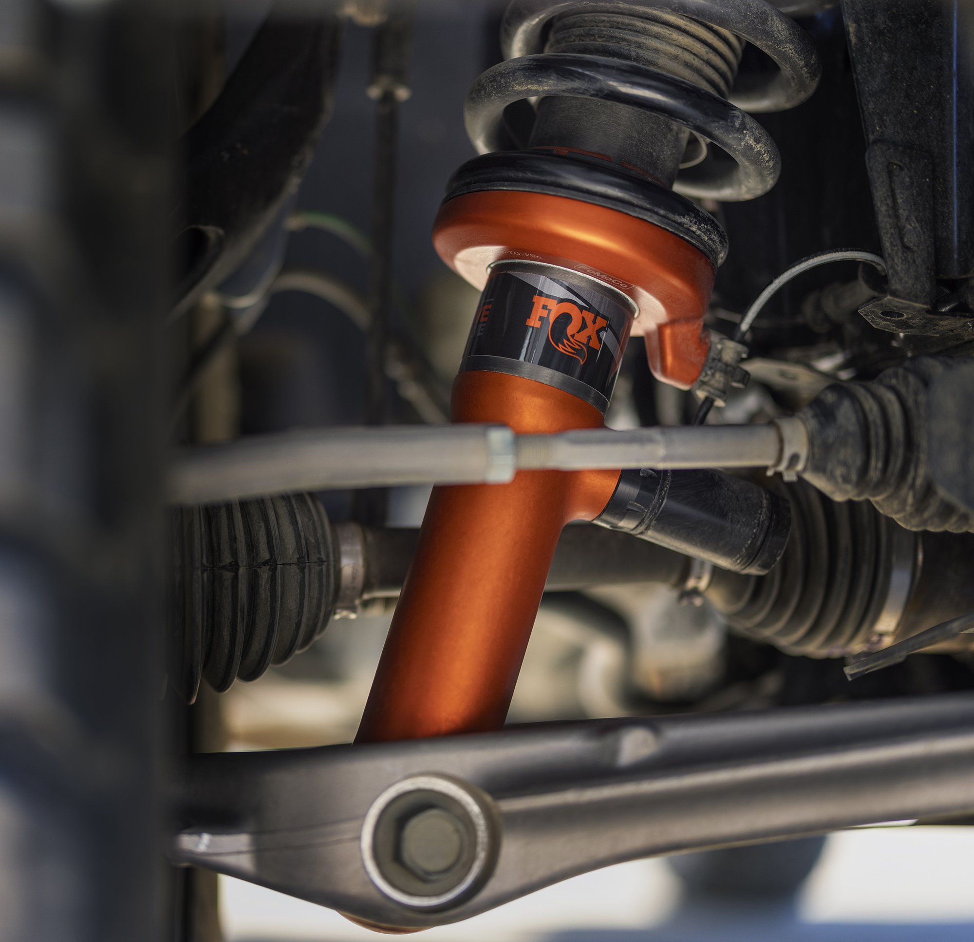 A close-up product shot of a high-performance orange FOX™ Live Valve shock absorber