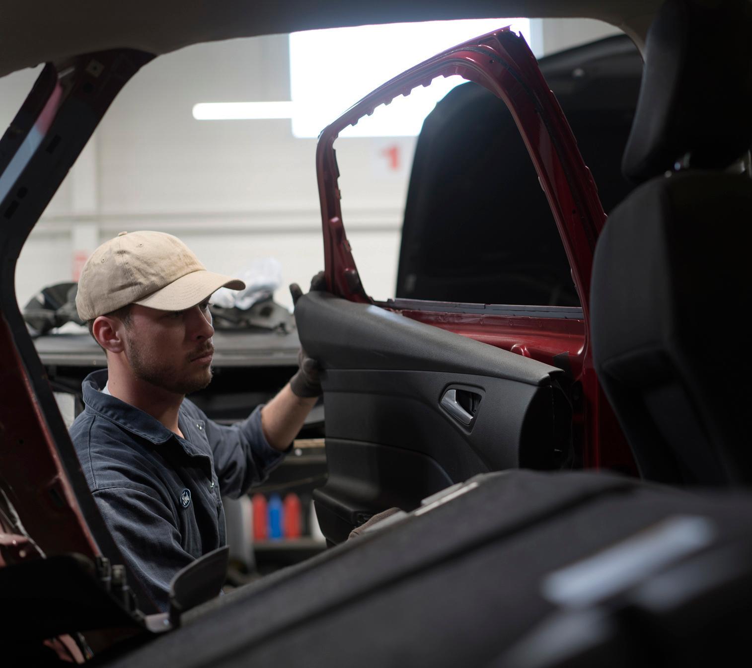 A Ford technician repairs a door