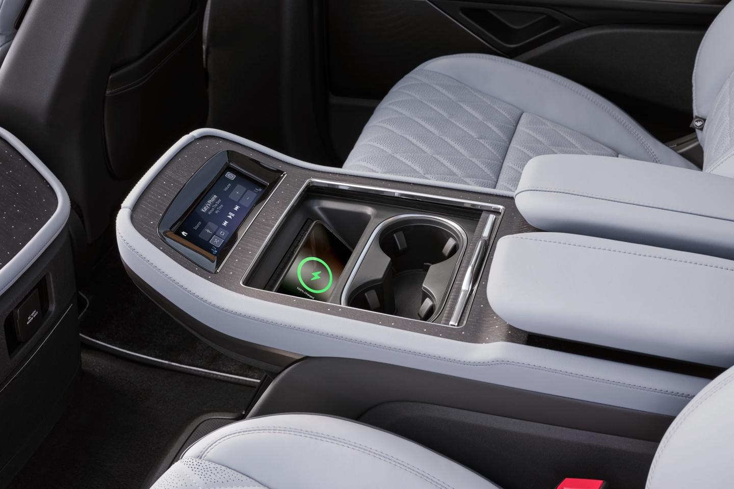 A phone charges on a wireless charging pad in the second row console of a 2025 Lincoln Black Label Navigator® SUV